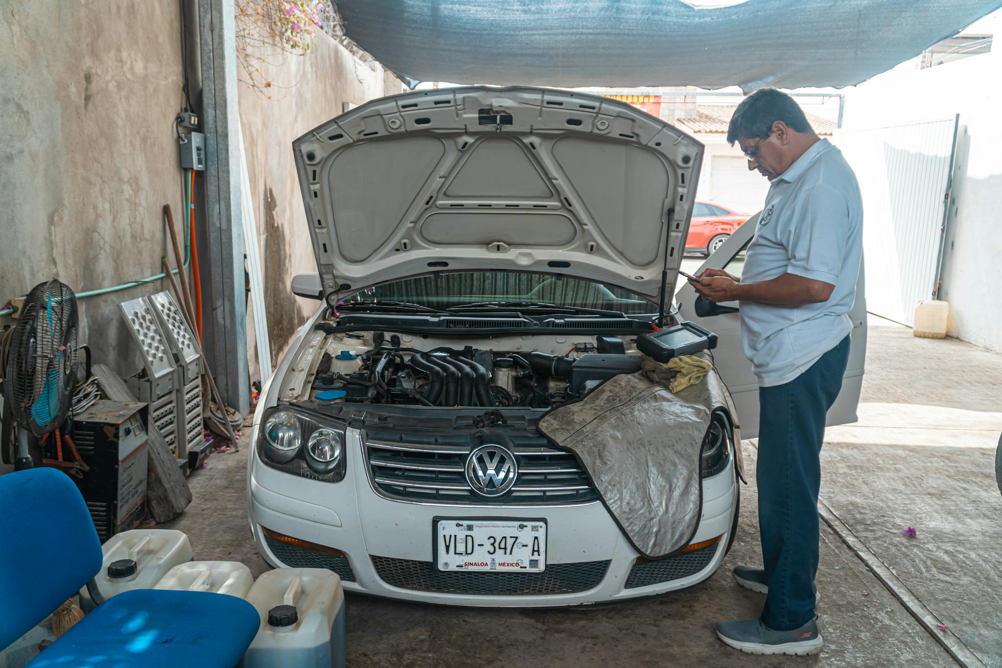 A mechanic examines a Volkswagen engine in a garage setting, focusing on car maintenance.