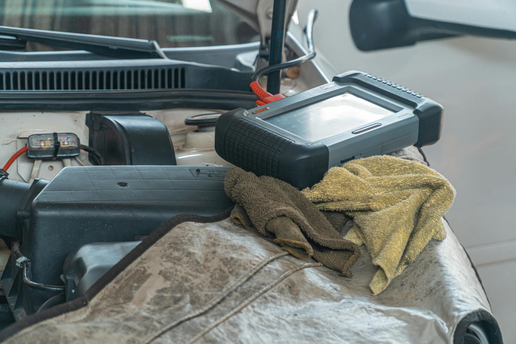 Close-up of car diagnostics tool on engine in a garage setting.